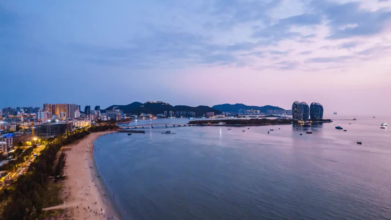 中国海南三亚凤凰岛和穿梭的游艇城市风光夜景延时摄影视频素材