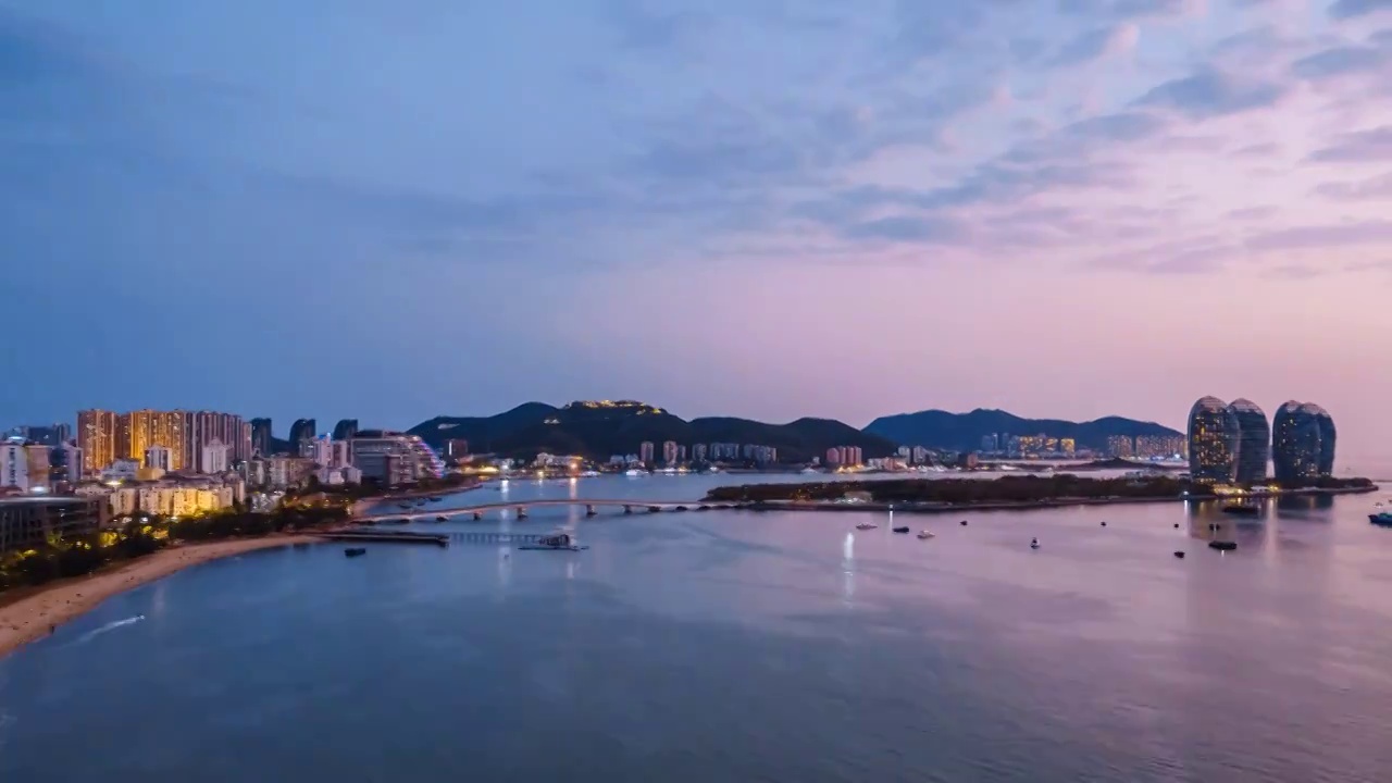 中国海南三亚凤凰岛和穿梭的游艇城市风光夜景延时摄影视频素材