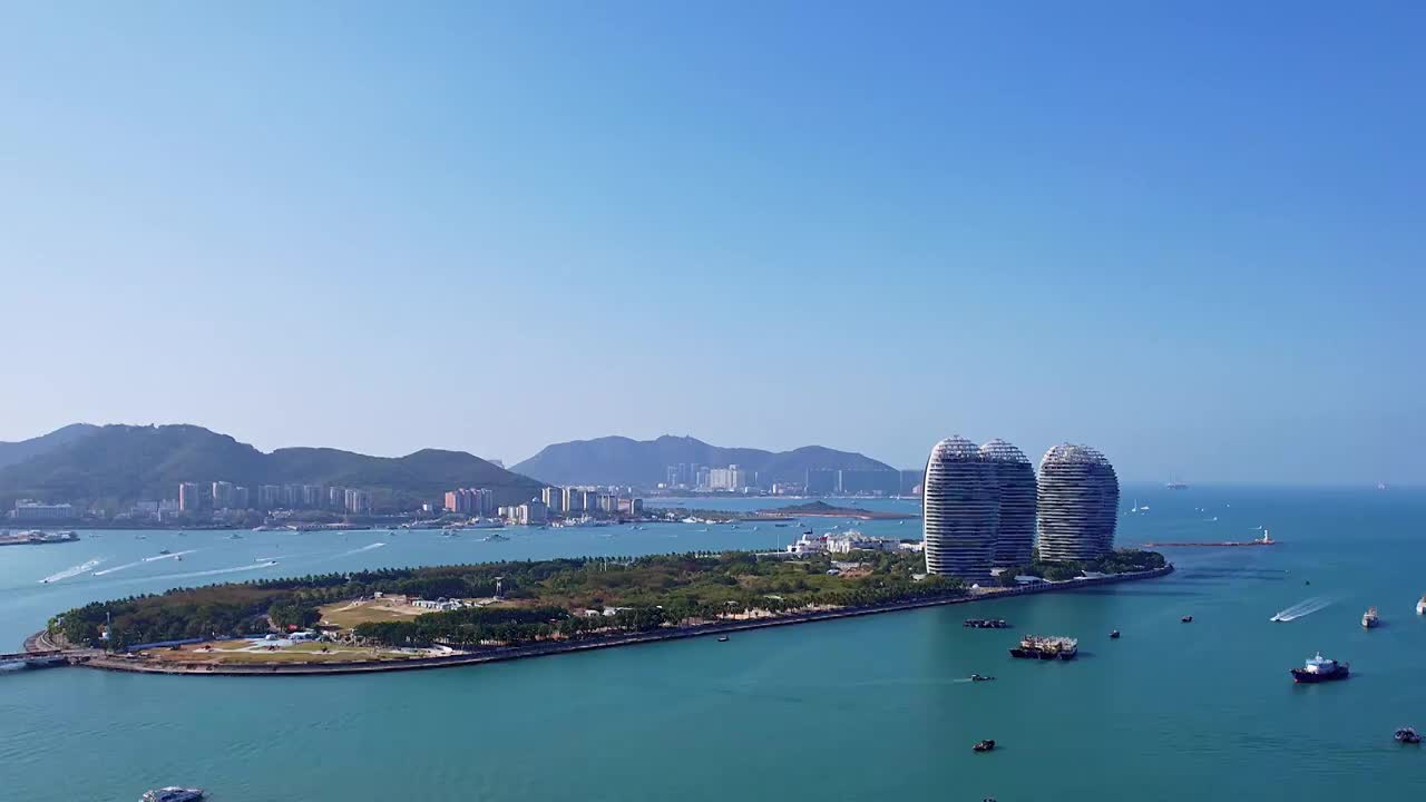 中国海南三亚三亚湾穿梭的游艇凤凰岛和城市天际线风光航拍视频素材