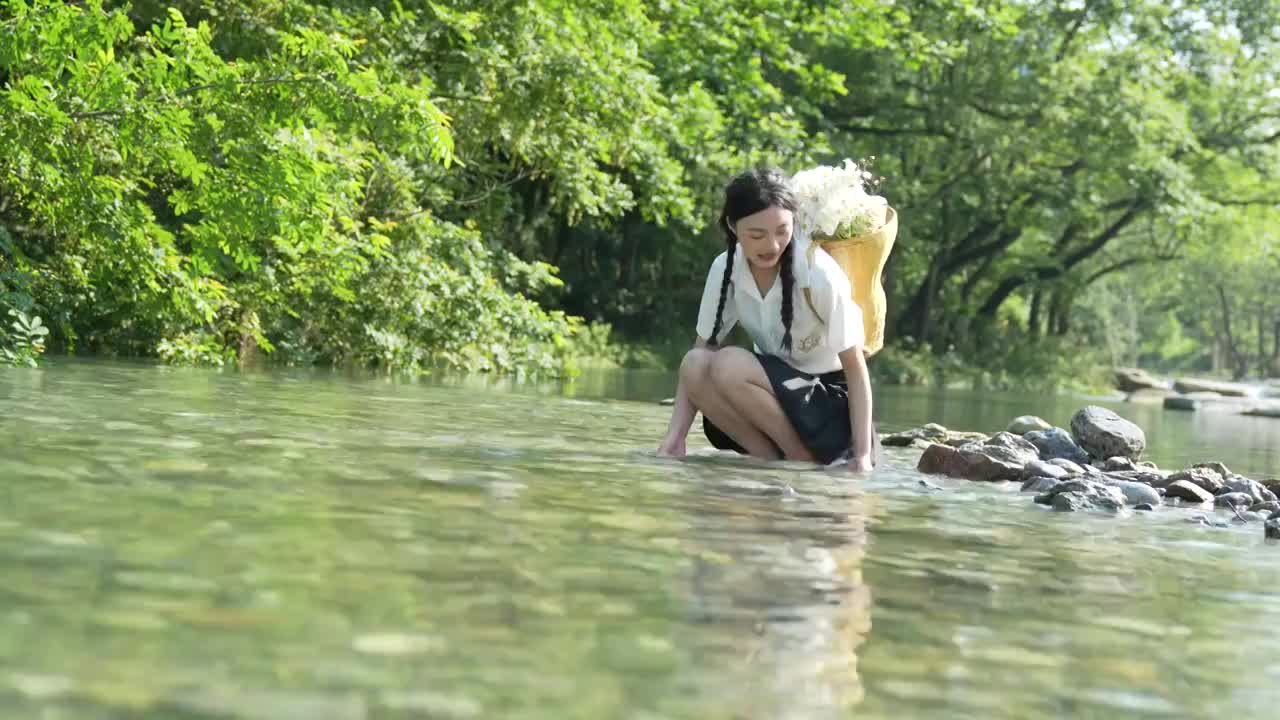 一位美女大学生在湖北宣恩撒野露营小镇河边玩水视频素材