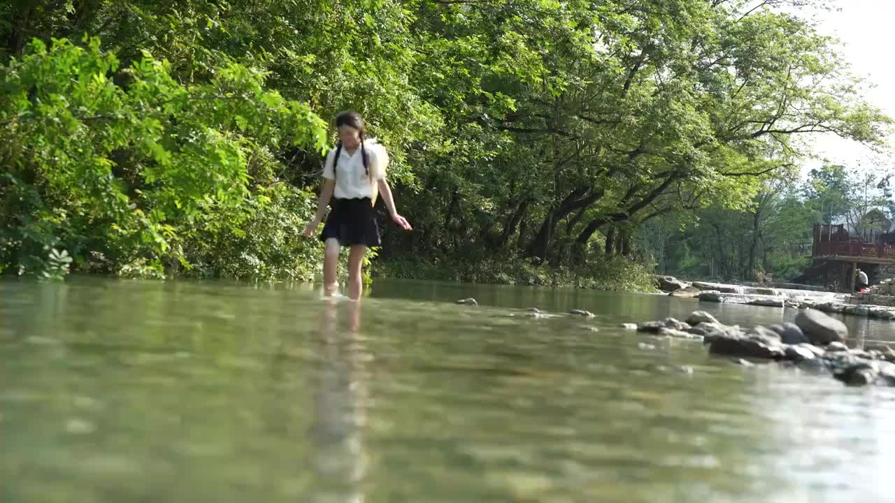 一位美女大学生在湖北宣恩撒野露营小镇河边玩水视频素材