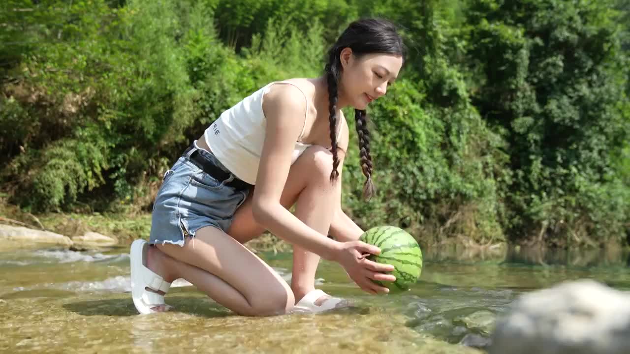 一位健康美女在湖北宣恩撒野露营小镇河边洗西瓜视频素材