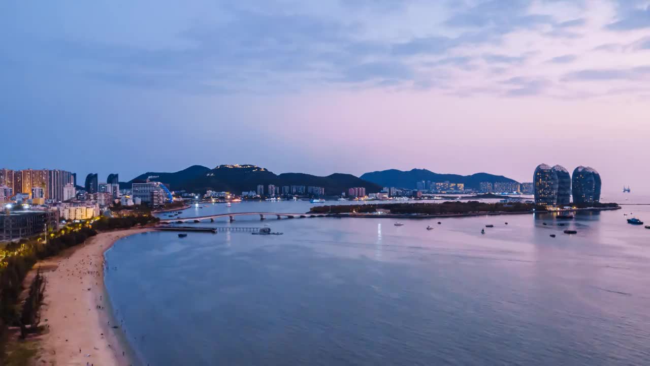 中国海南三亚凤凰岛和穿梭的游艇城市风光夜景延时摄影视频素材