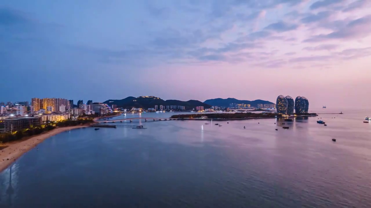 中国海南三亚凤凰岛和穿梭的游艇城市风光夜景延时摄影视频素材