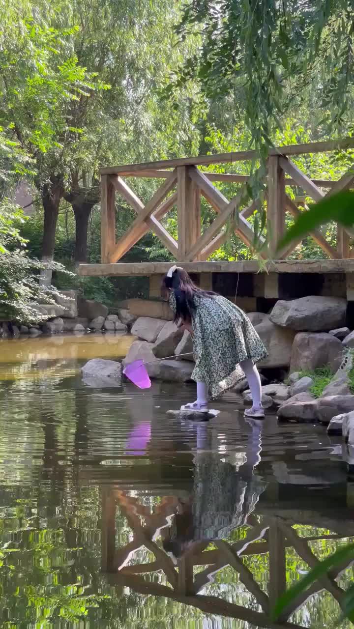 一个小女孩儿在池塘边打捞小鱼视频素材