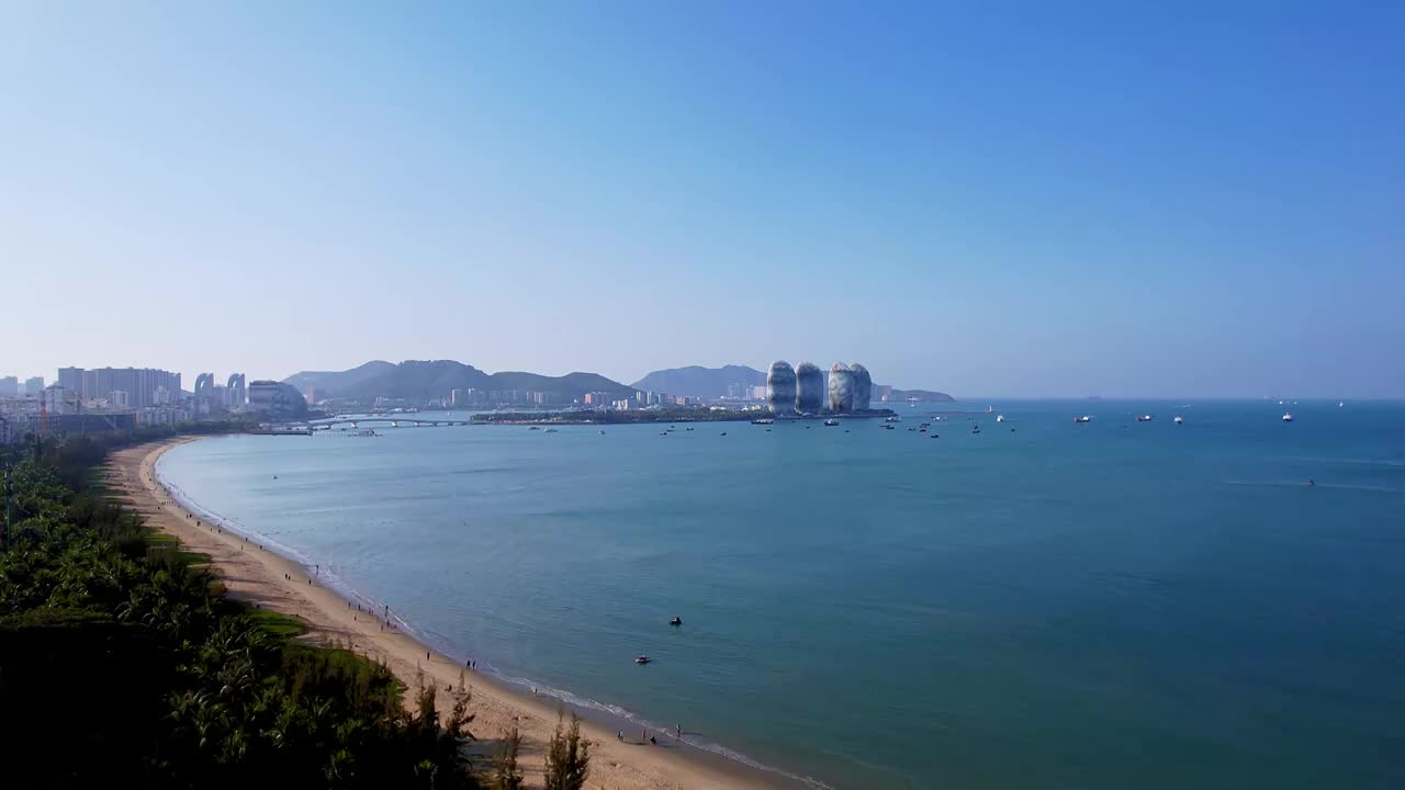 中国海南三亚三亚湾海岸线凤凰岛和城市天际线风光航拍视频素材