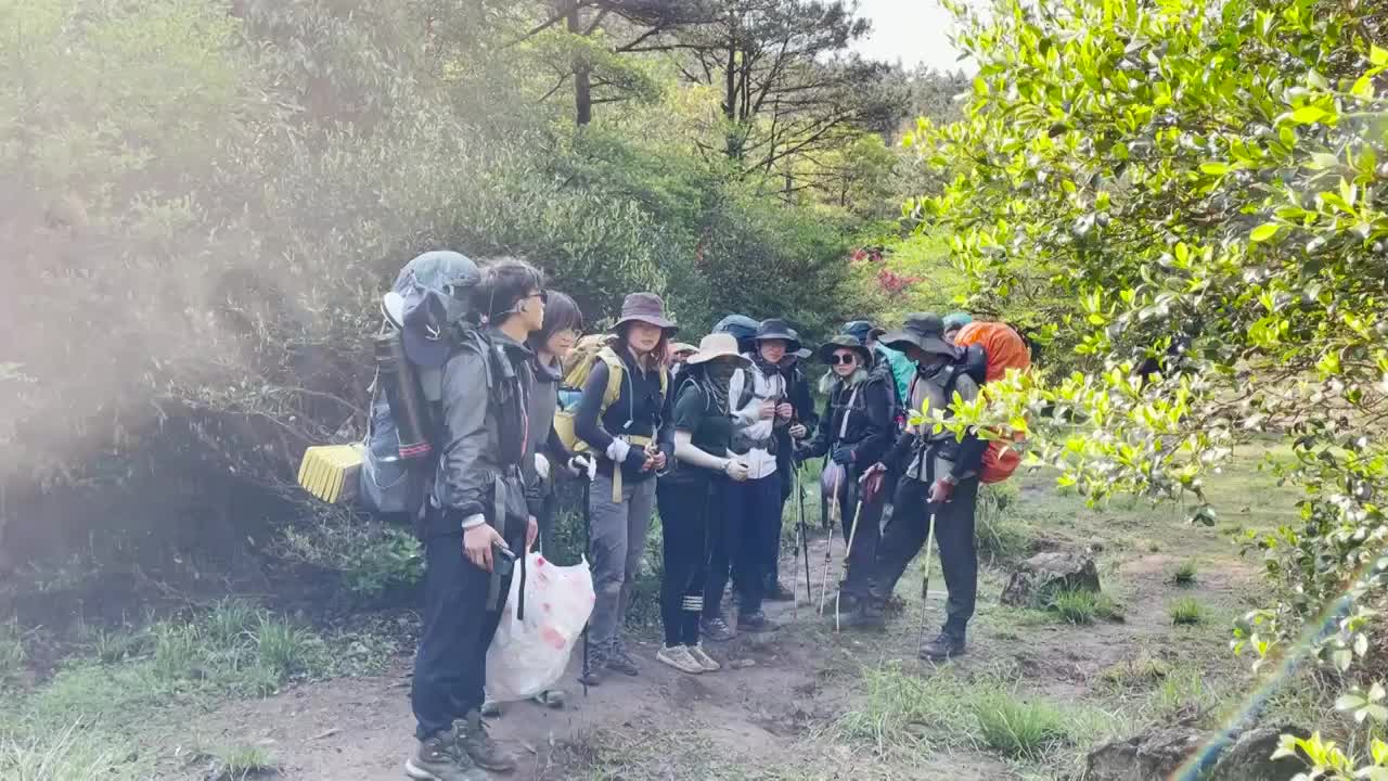 登山者提着垃圾在驻足商量如何登山背着大书包视频下载