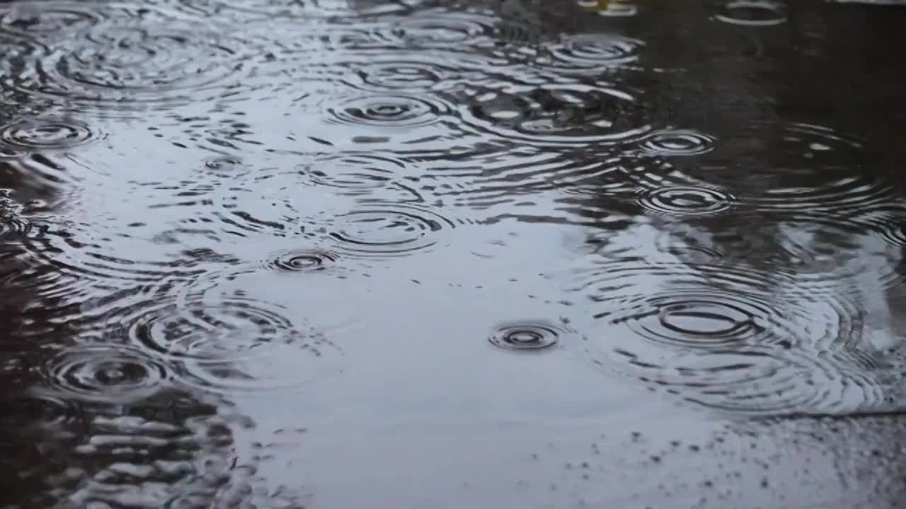 下雨天雨水雨滴落在积水的路面上视频素材