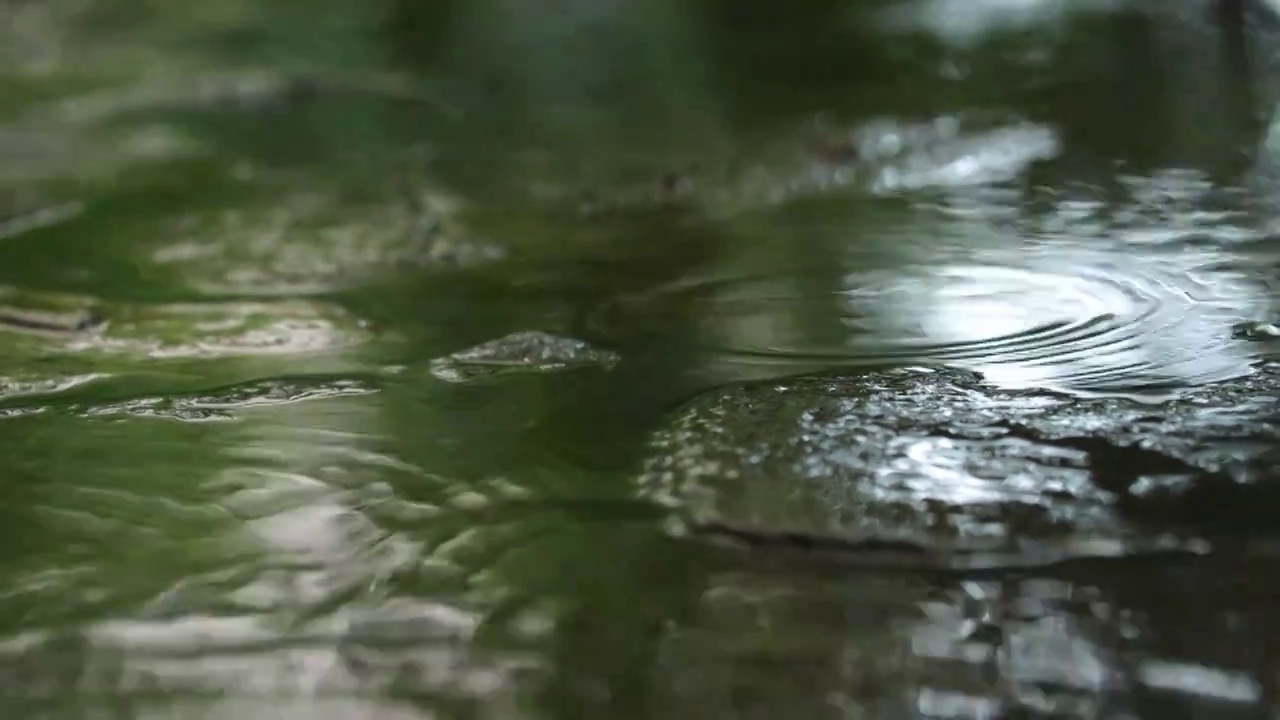 下雨天雨水雨滴落在积水的路面上视频素材