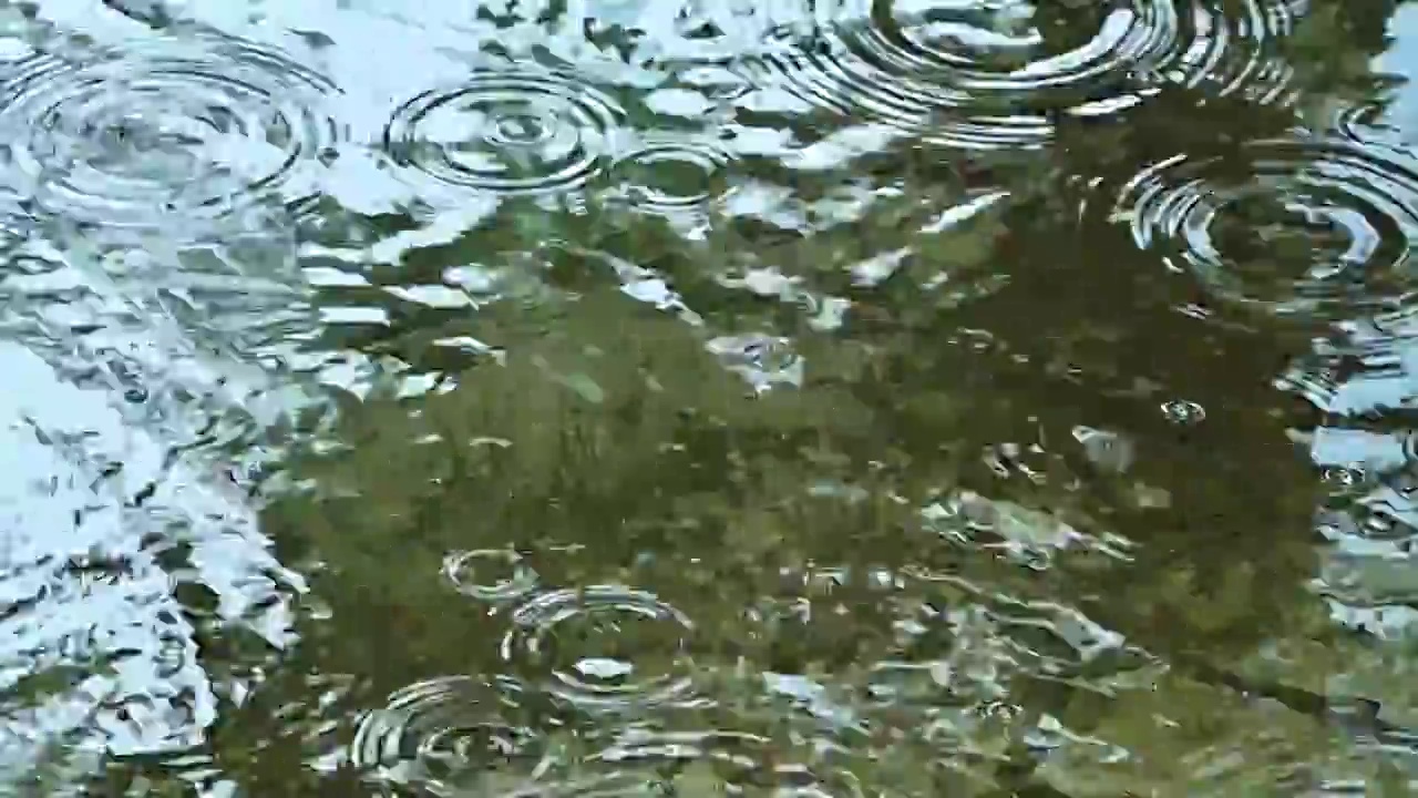 雨滴滴落在积水的水面上溅起水波纹涟漪视频素材