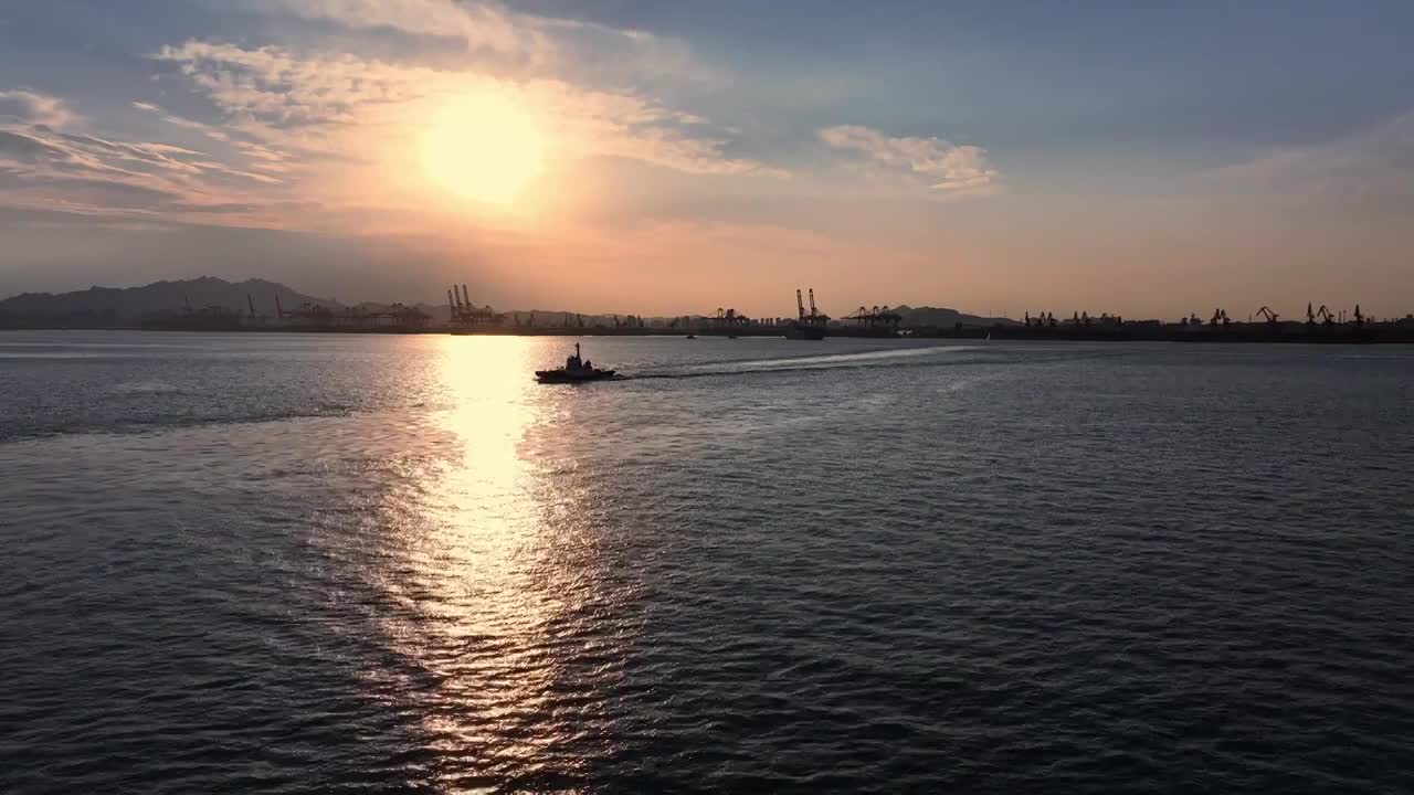 傍晚夕阳下胶州湾青岛港里行驶的邮轮和拖船，太阳阳光港口码头货物运输海运，进出口贸易集装箱视频素材