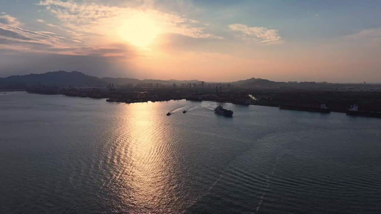 傍晚夕阳下胶州湾青岛港里行驶的邮轮和拖船，太阳阳光港口码头货物运输海运，进出口贸易集装箱视频素材