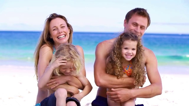 父母在海滩上拥抱他们的孩子视频素材画面4