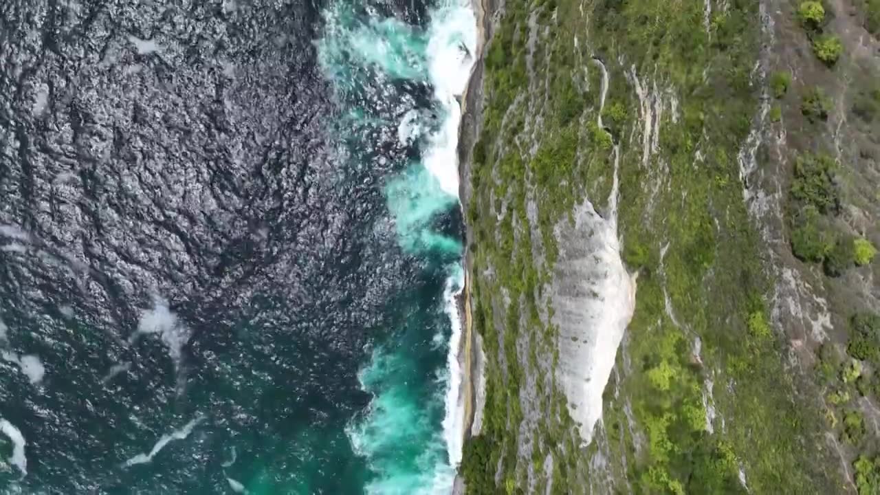 航拍印尼巴厘岛热带雨林悬崖下的绿松石海水波浪视频素材