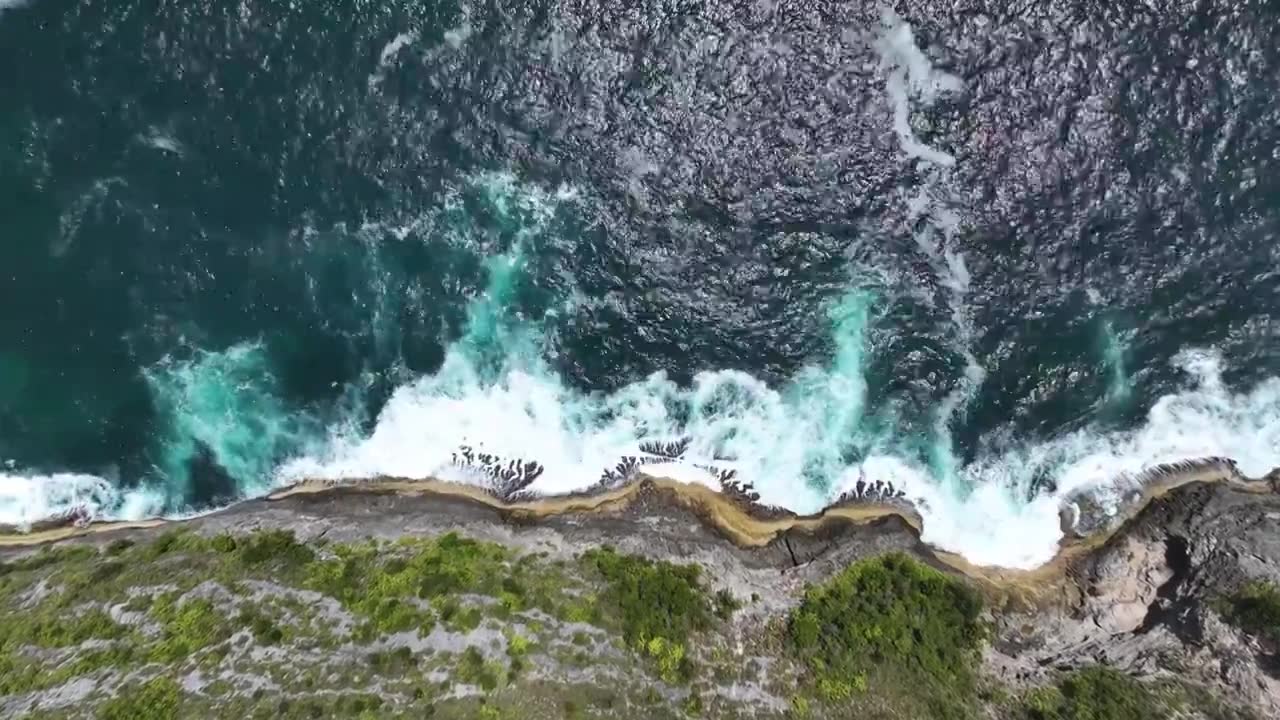 航拍印尼巴厘岛热带雨林悬崖下的绿松石海水波浪视频素材