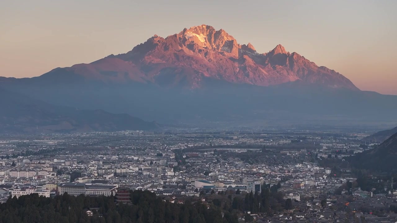 航拍视角下的云南丽江玉龙雪山日出日照金山和城市天际线视频素材