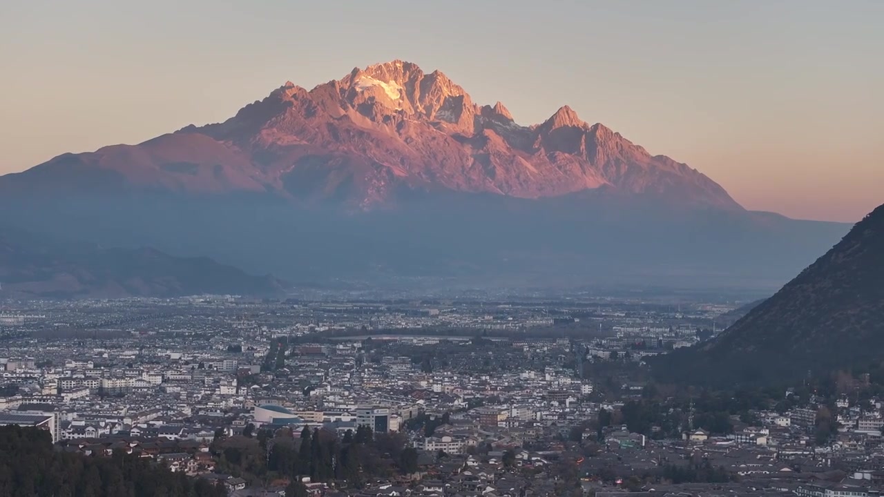 航拍视角下的云南丽江玉龙雪山日出日照金山和城市天际线视频素材