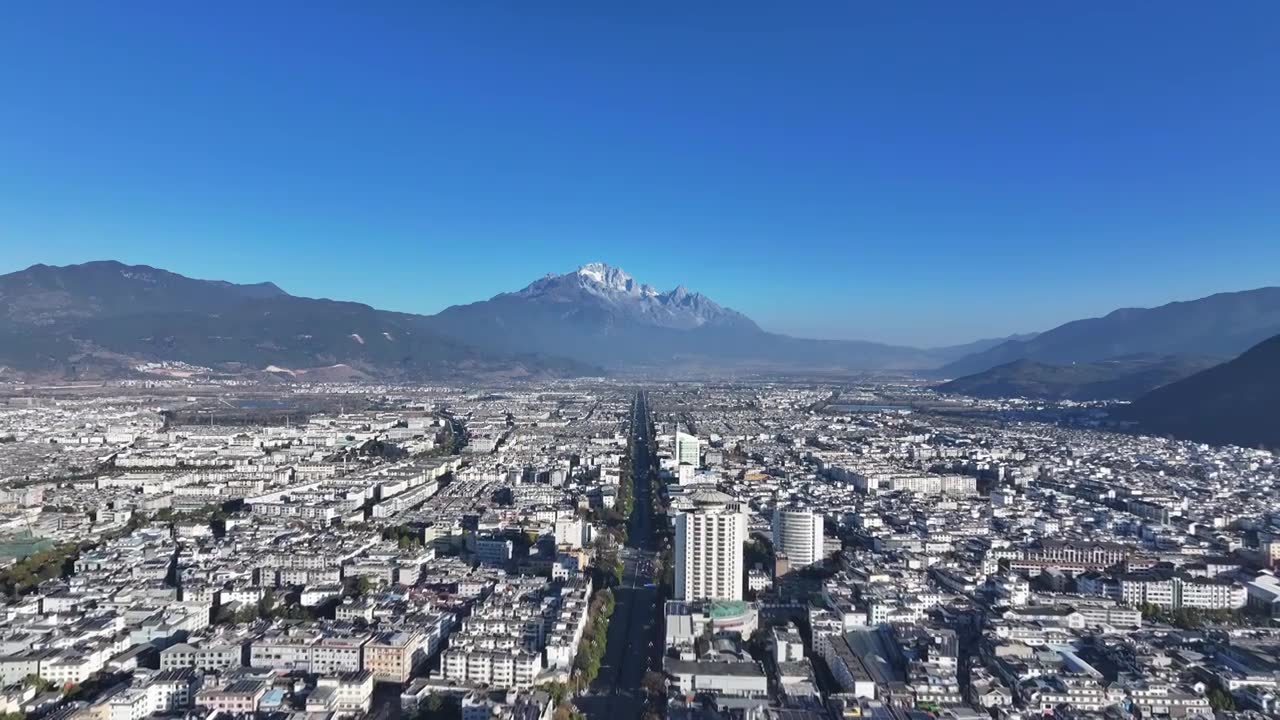 航拍视角下的云南丽江玉龙雪山和城市天际线白昼风光视频素材