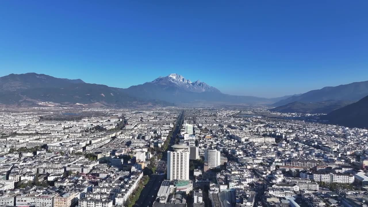 航拍视角下的云南丽江玉龙雪山和城市天际线白昼风光视频素材