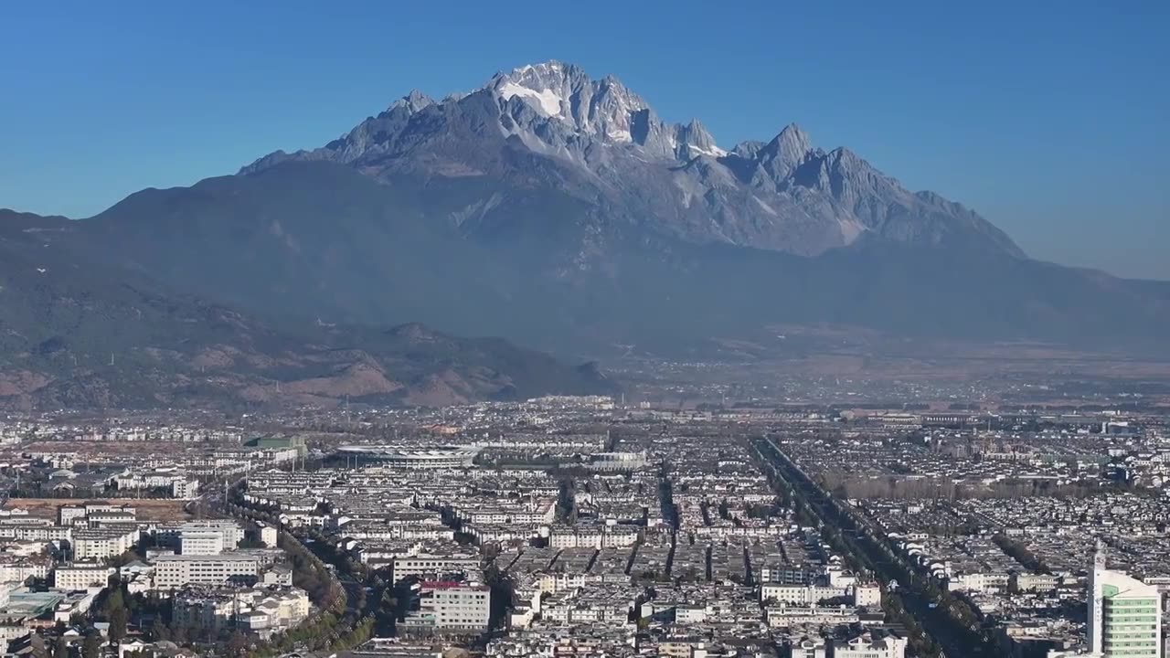 航拍视角下的云南丽江玉龙雪山和城市天际线白昼风光视频素材