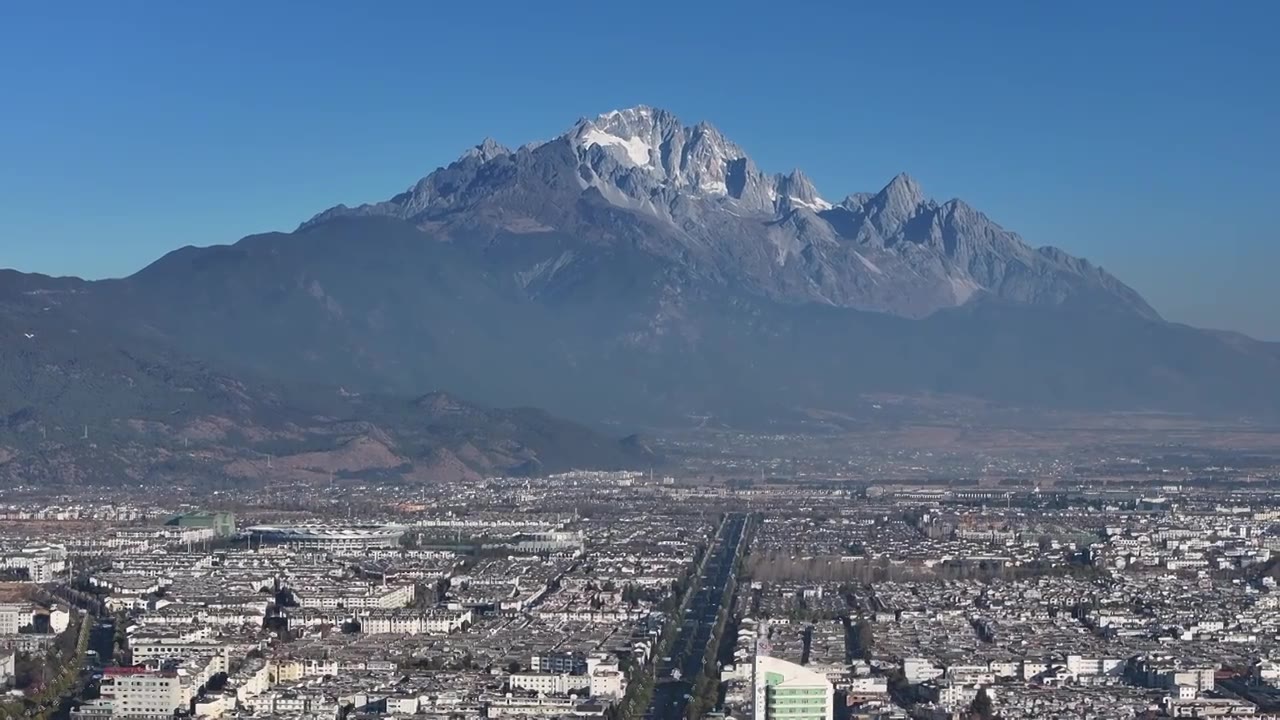 航拍视角下的云南丽江玉龙雪山和城市天际线白昼风光视频素材