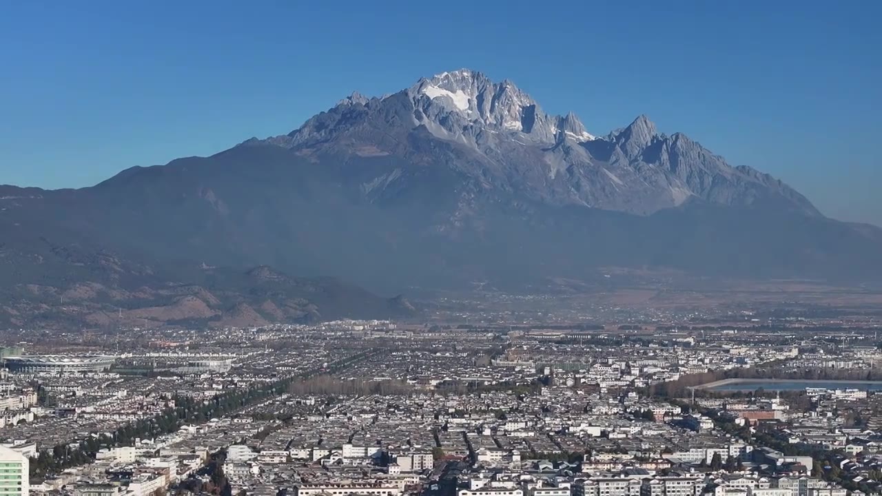 航拍视角下的云南丽江玉龙雪山和城市天际线白昼风光视频素材