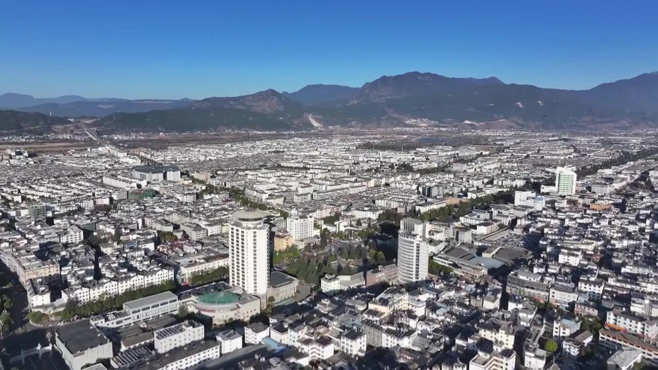 航拍视角下的云南丽江玉龙雪山和城市天际线白昼风光视频素材