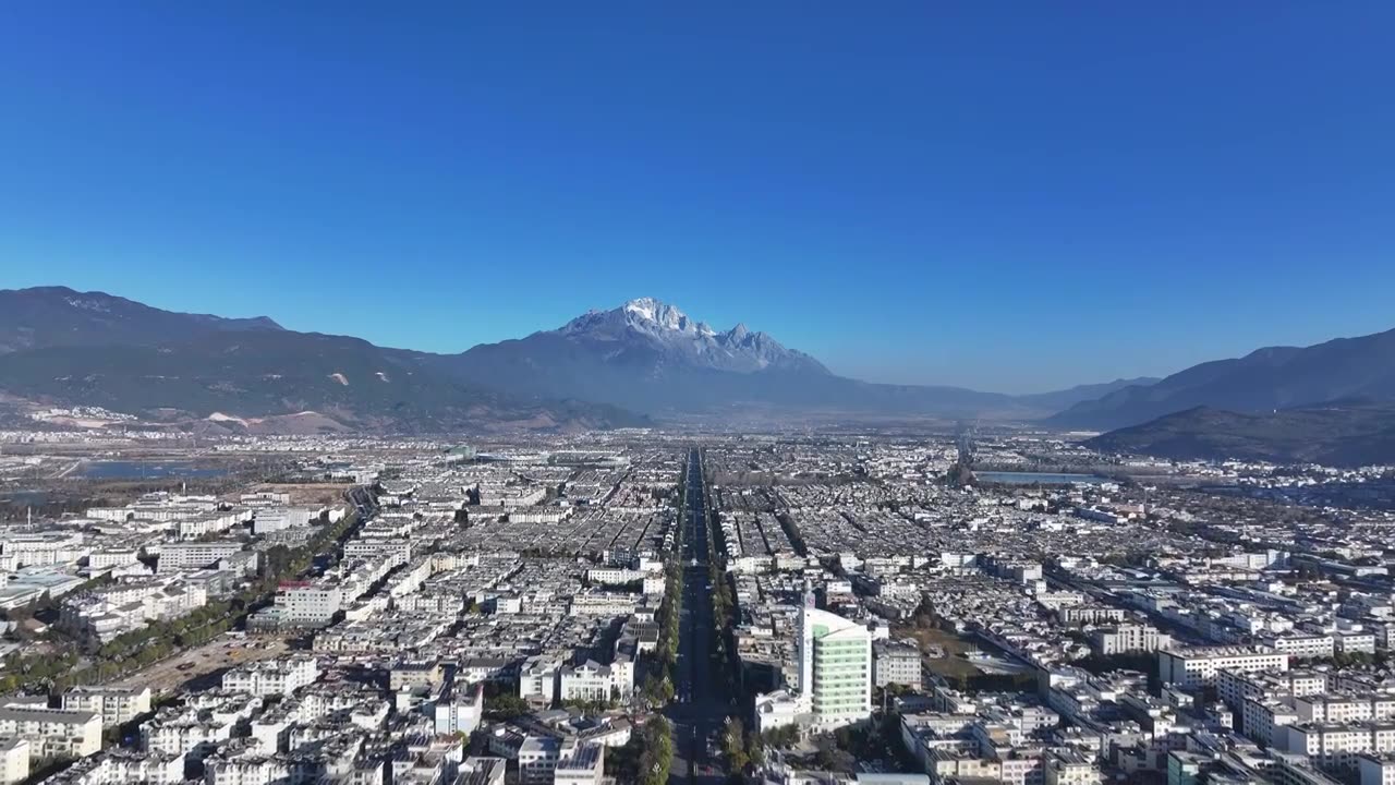 航拍视角下的云南丽江玉龙雪山和城市天际线白昼风光视频素材