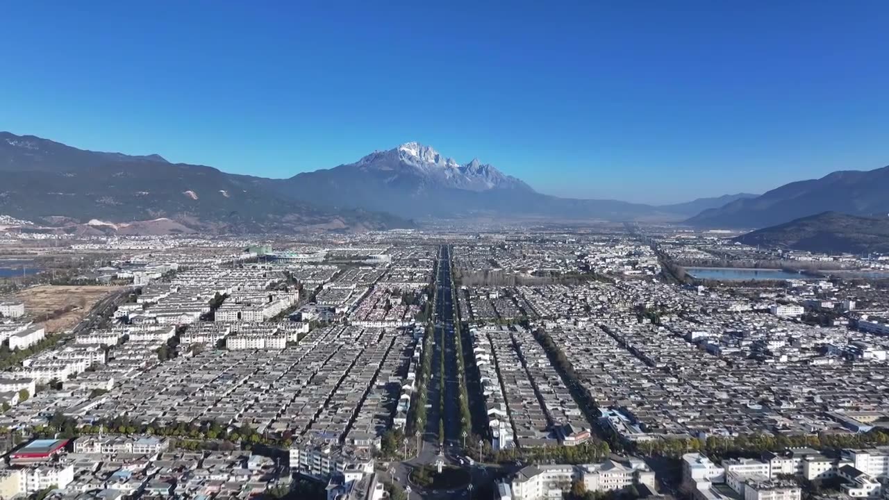 航拍视角下的云南丽江玉龙雪山和城市天际线白昼风光视频素材