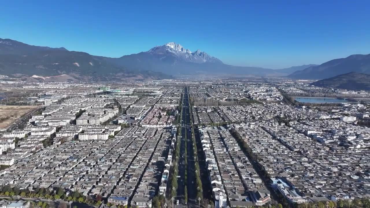 航拍视角下的云南丽江玉龙雪山和城市天际线白昼风光视频素材