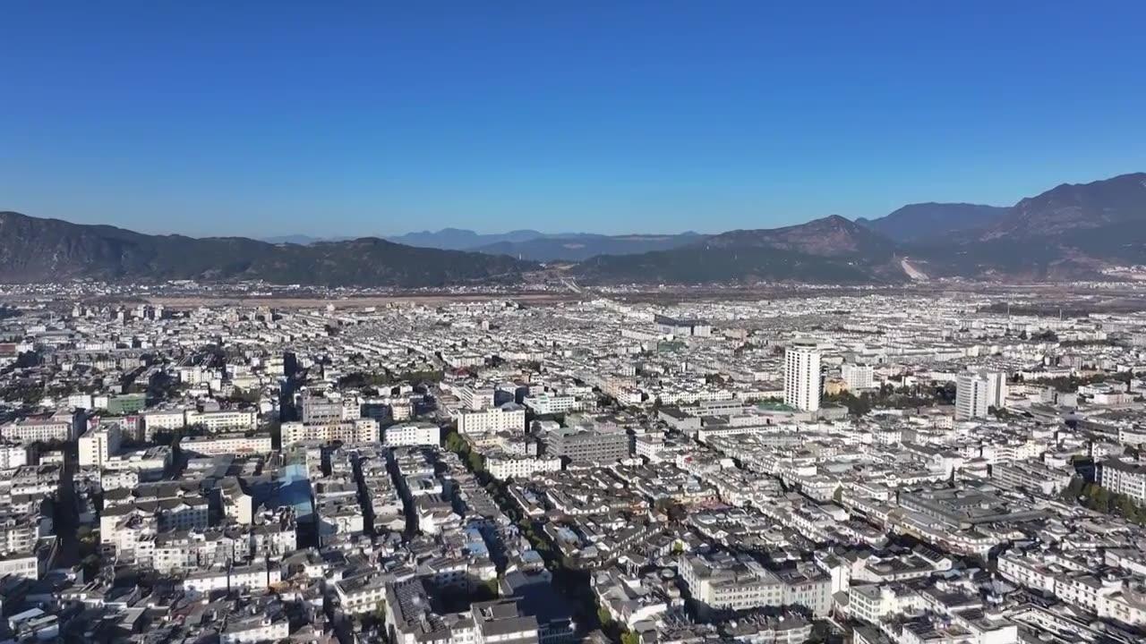 航拍视角下的云南丽江玉龙雪山和城市天际线白昼风光视频素材