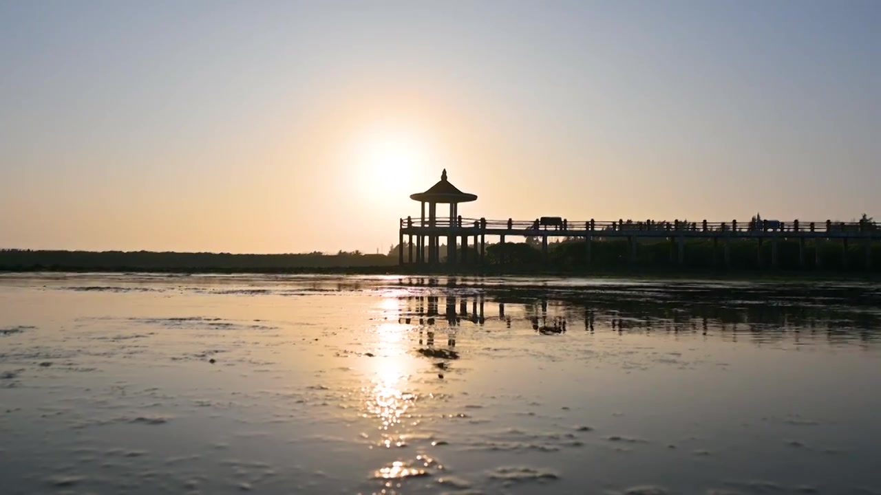 夕阳下海边退潮后滩涂与亭子剪影视频素材