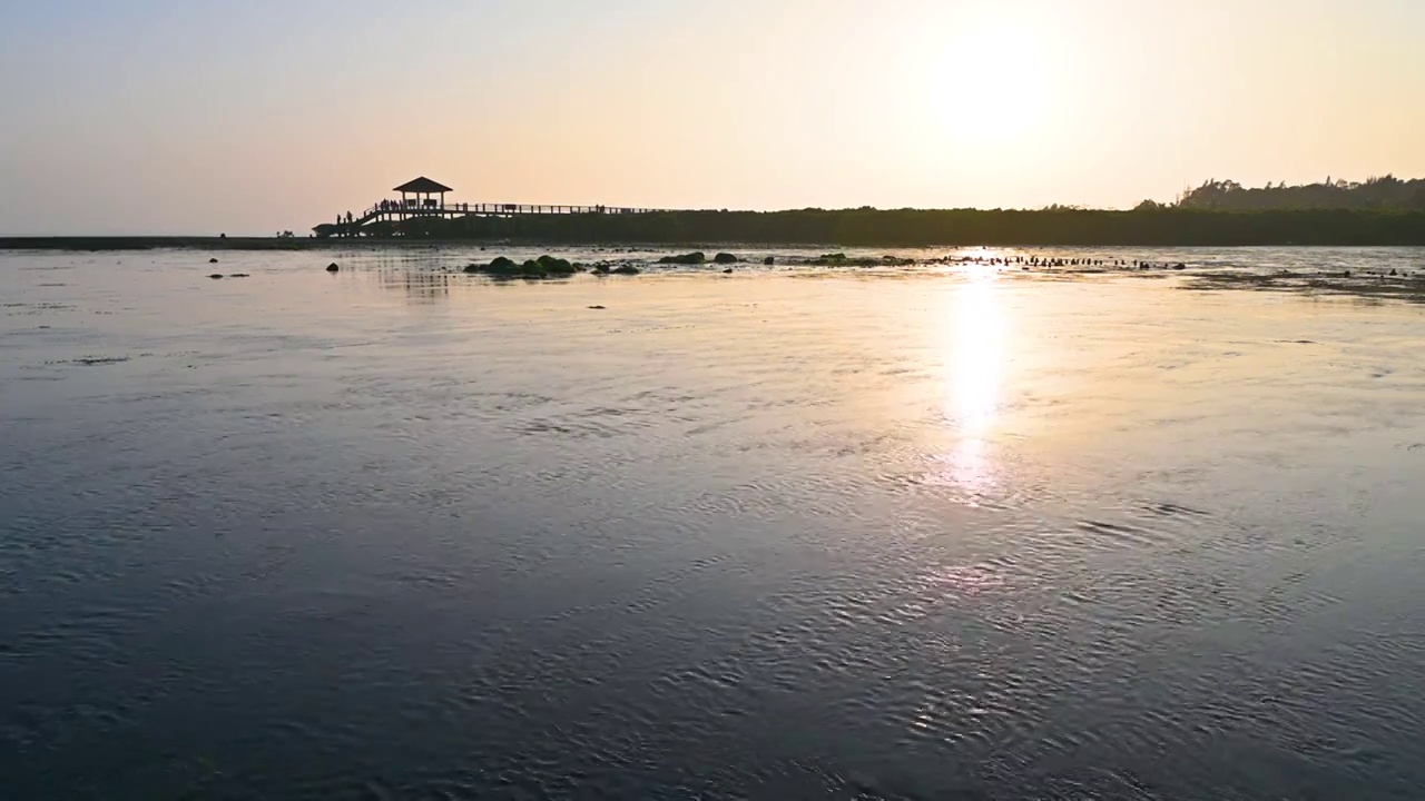 夕阳下海边退潮后滩涂与亭子剪影视频素材