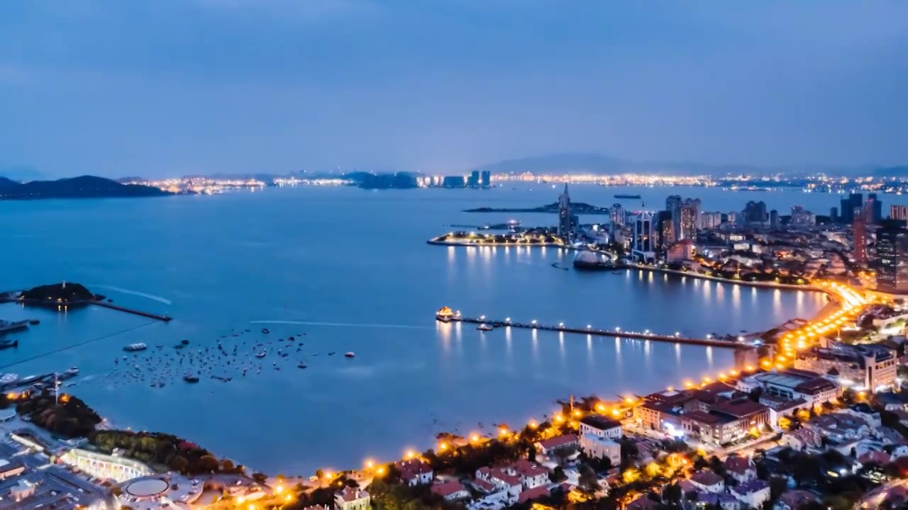 中国山东青岛栈桥和市南区城市天际线夜景航拍延时摄影视频素材