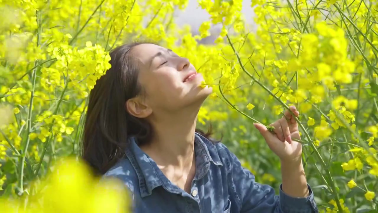 美女在油菜花地里享受春天阳光温暖视频素材