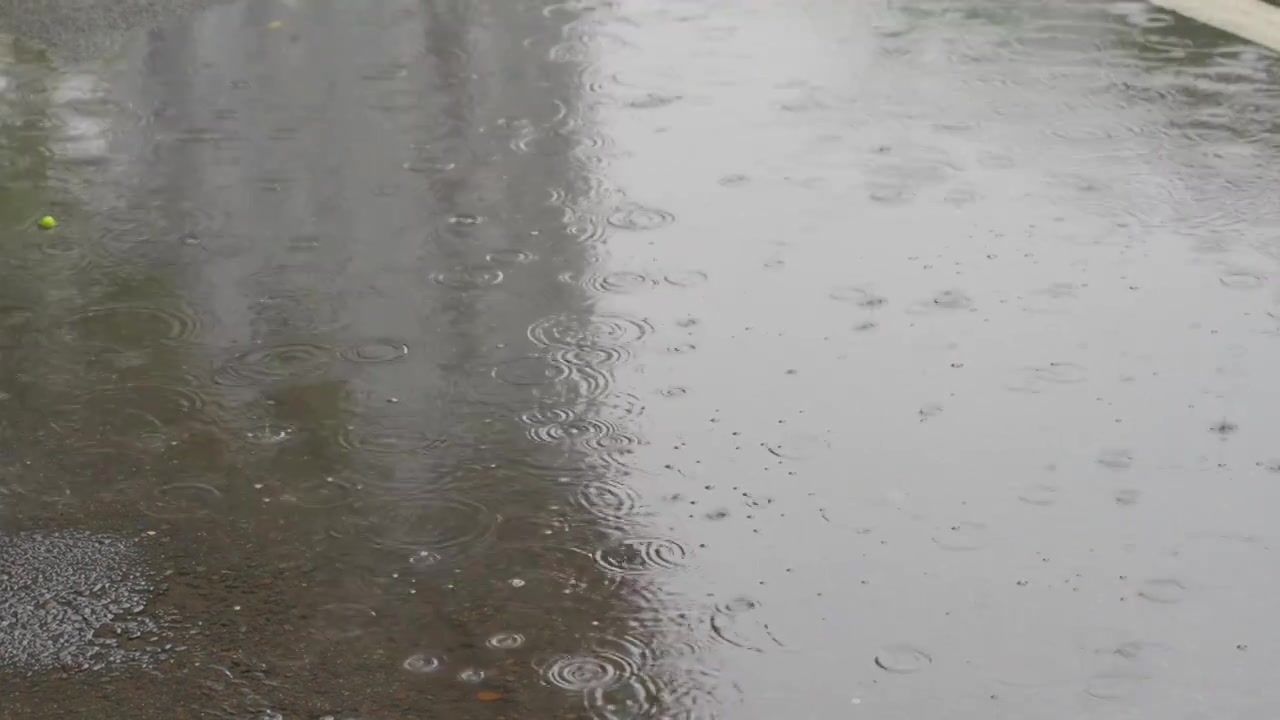 下雨天暴雨天雨滴落在马路积水上形成水坑慢镜头视频素材