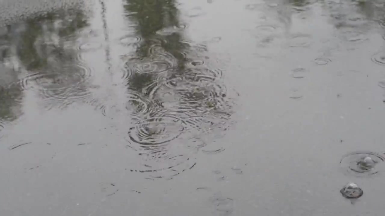 下雨天暴雨天雨滴落在马路积水上形成水坑视频素材