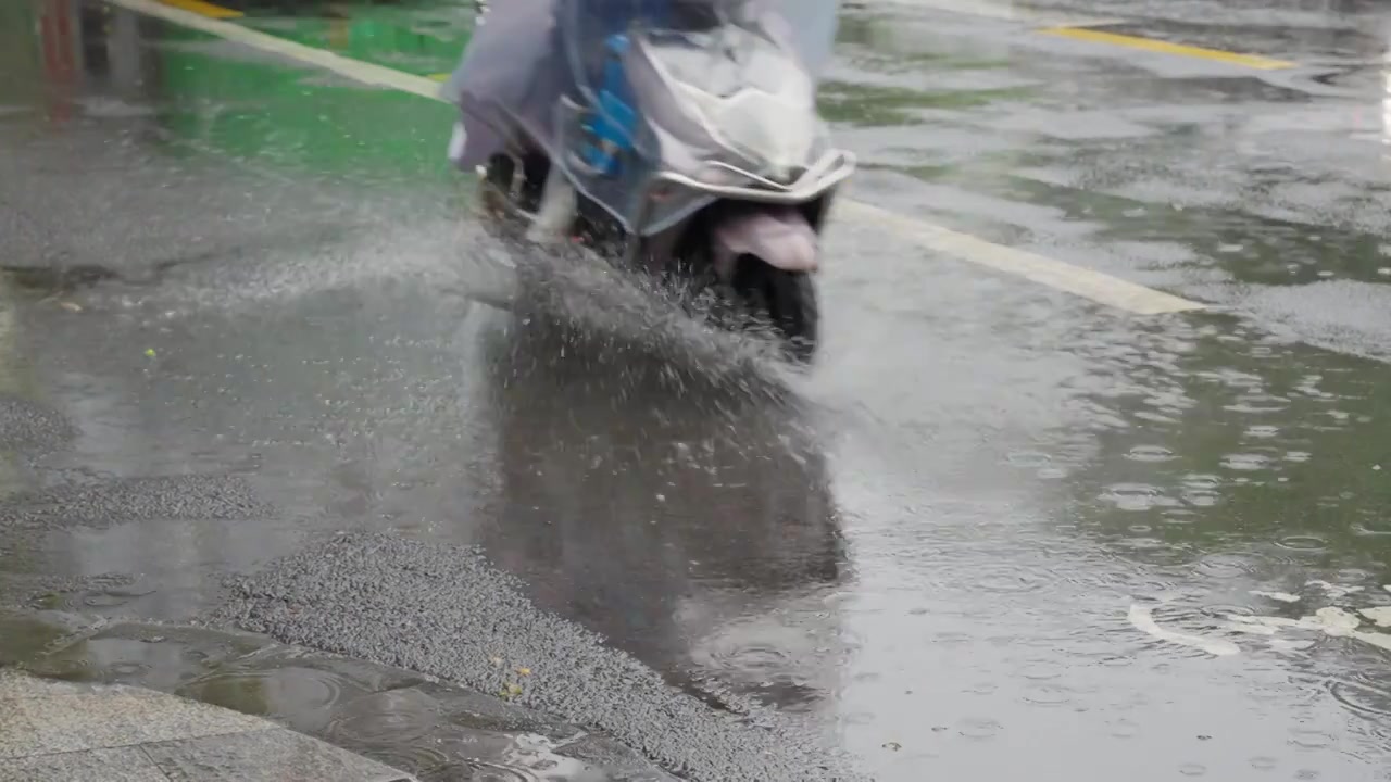 下雨天暴雨天气电动车路过街道积水溅起水花慢镜头视频素材