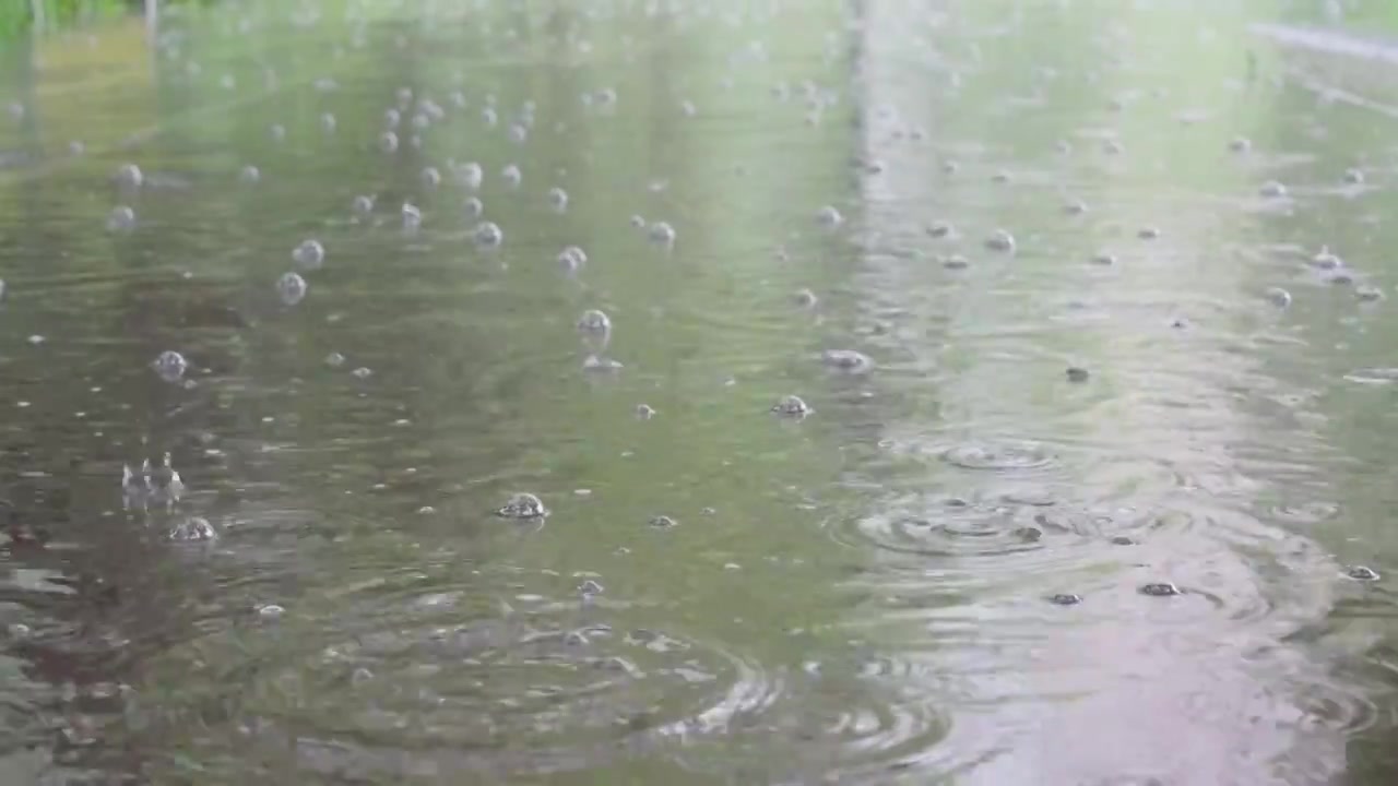 暴雨雨滴落在路面积水水坑，溅起涟漪波纹水花水泡慢镜头升格，暴雨内涝自然灾害概念视频素材