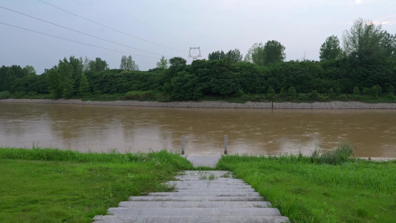 连续多日的雨季让陕西西安境内河流的水位暴涨，清水河变成了混浊的浊水河，河水与岸边的绿色草地视频素材