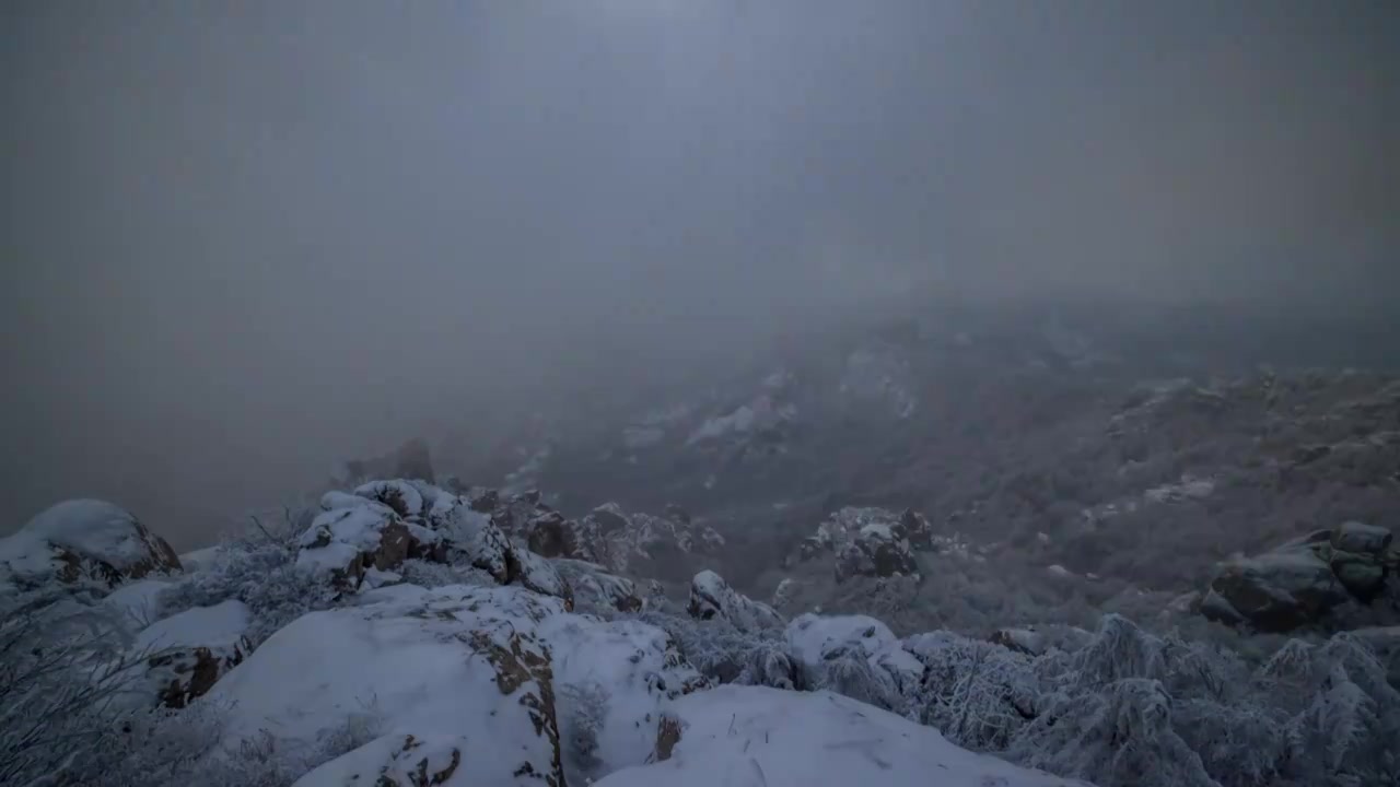 冬季青岛崂山巨峰景区的雪后日出，漫山覆盖了厚厚的白雪，云在山谷间穿过，太阳在云后若隐若现视频素材