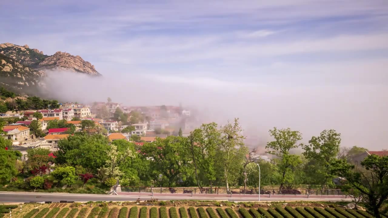 青岛崂山里的海边村庄，平流雾海上袭来，绿荫与红瓦白墙的村庄在雾气若隐若现，更显得迷人视频下载