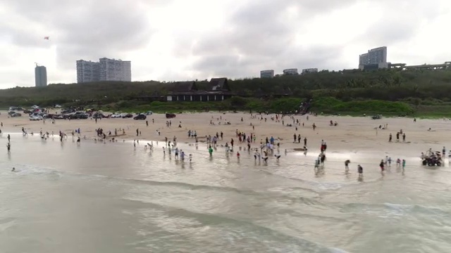 航拍文昌高隆湾夕阳下玩耍的人群视频素材