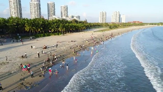 航拍文昌高隆湾夕阳下玩耍的人群视频素材