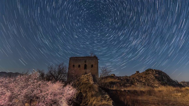 中国河北省涞源县王安镇烟煤洞南楼台长城桃花盛开月夜星轨视频素材