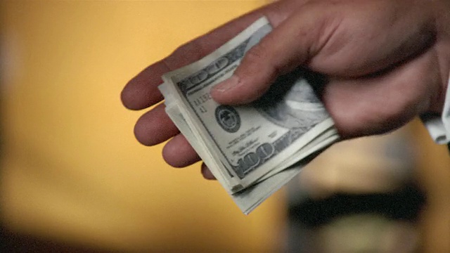 折叠的100美元钞票在两名男子之间交换双手的特写视频购买