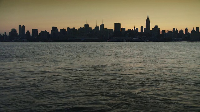 一个完整的曼哈顿城市景观与哈德逊河在前景。清晨金色的天空视频素材