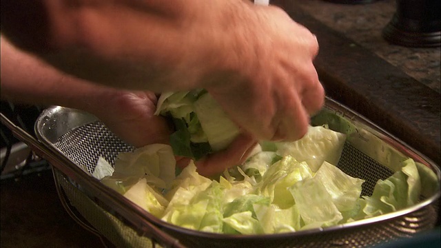 特写:一名食品服务人员用筛子清洗生菜叶子视频素材