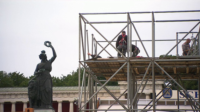 建筑工人在脚手架上搭建啤酒节，背景是“巴伐利亚”雕像视频素材