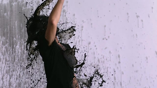 MS SLO MO拍摄的一名亚洲男子站在白色背景下，将黑色液体从一个大容器中倒入嘴里并喷在脸上。/ Studio，纽约，美国视频素材画面2